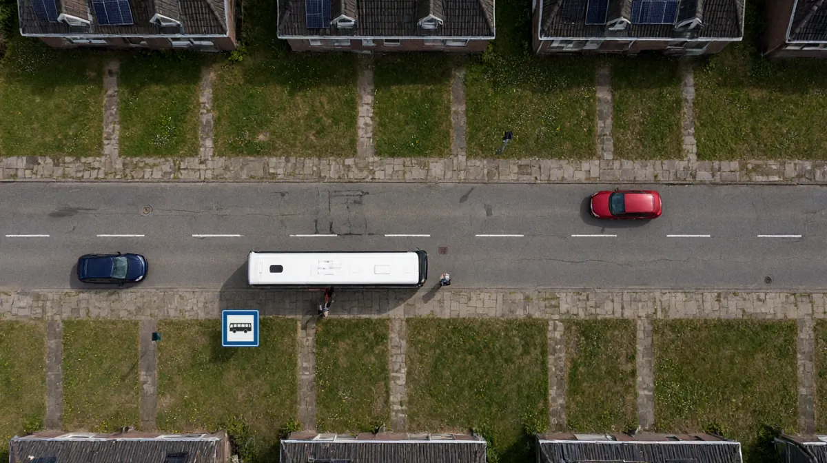 Bovenaanzicht van een straat. Een bus staat stil bij een halte; een passagier stapt uit en een voetganger loopt van achter de bus de rijbaan op. De eigen auto wacht achter de bus; op de andere rijstrook komt een auto aan.